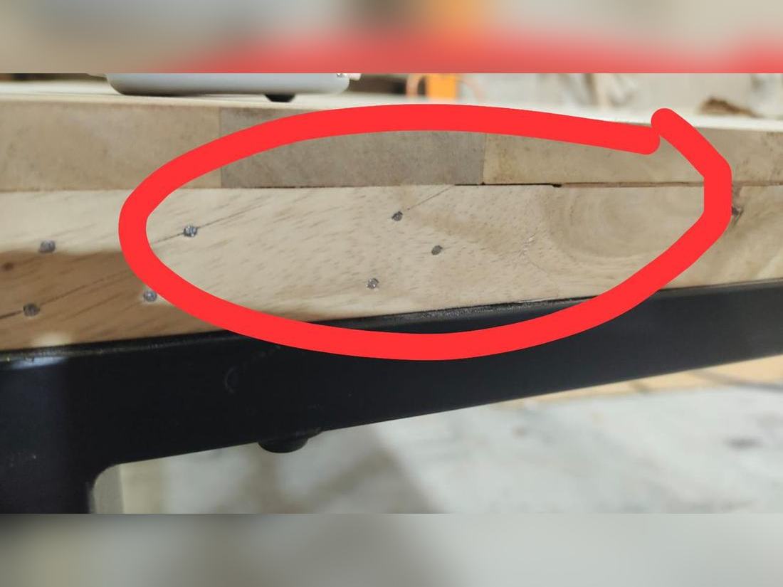 Gap opening along the glue line between two layers of a solid wood top edge, with nail heads showing, circled by the inspector.