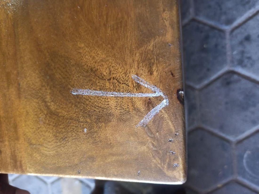 Solid wood top with poorly filled cracks, marked by the inspector with a chalk arrow at a pre-shipment inspection.