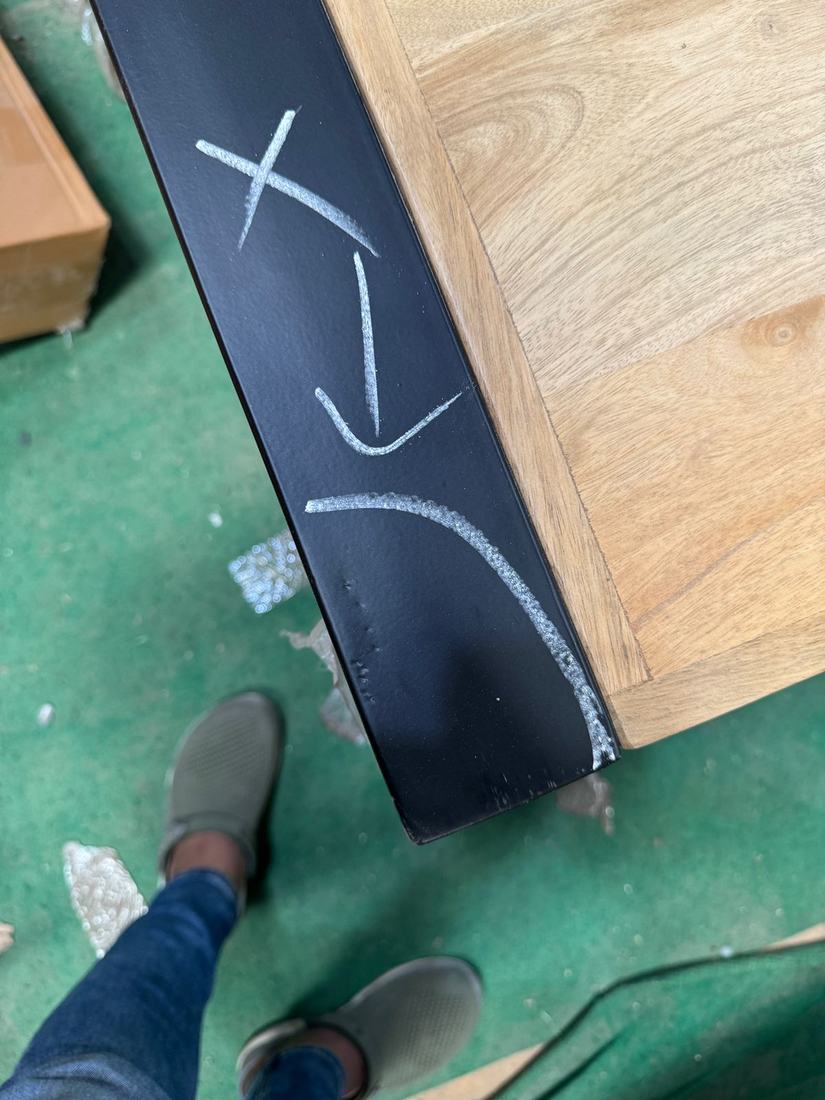 Chipped and dented coating near the foot of a black metal leg, marked in chalk