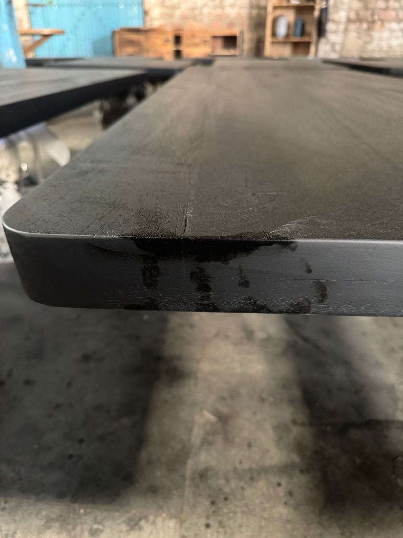 Crack at the corner of a black-finished top, with finish runs on the edge