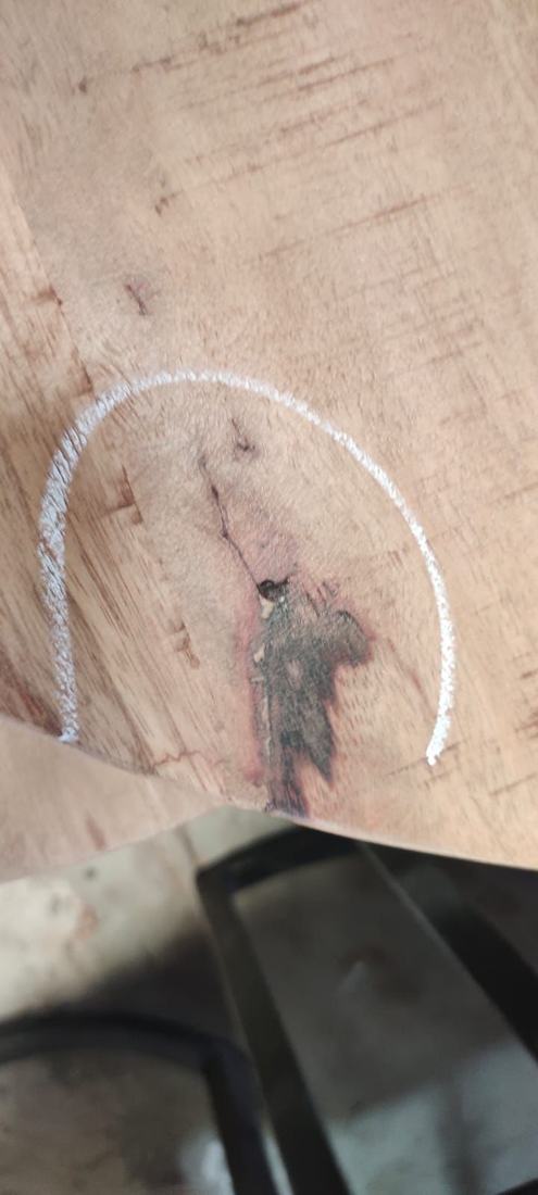 Crack running from a discoloured knot towards the edge of a top