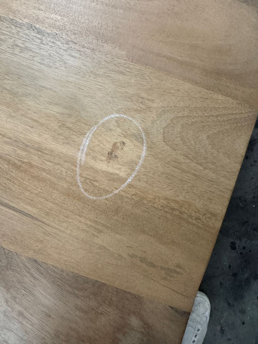 Dark mark in the surface of a light solid wood top, circled in chalk