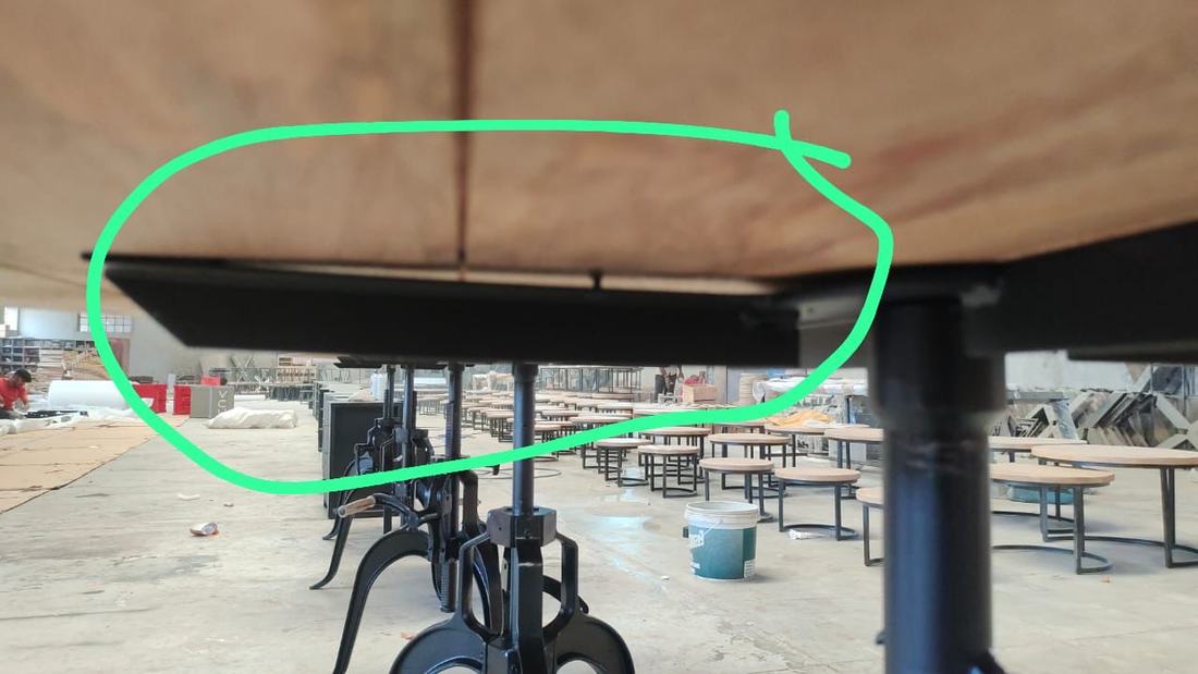 Gap between a metal table base and the wooden top, circled by the inspector