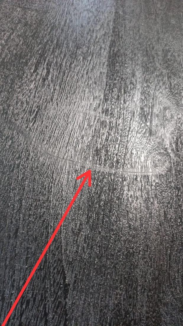 Hairline crack across the grain of a dark-finished solid wood top