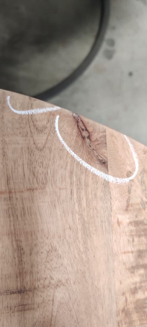 Dark knot with a crack near the edge of a round mango-wood top