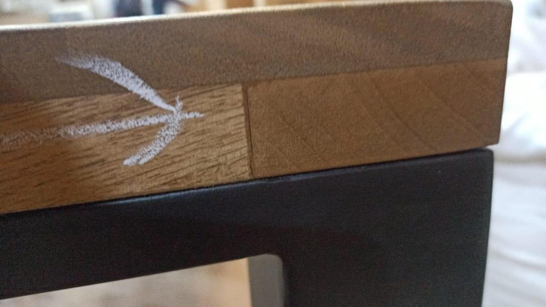 Open joint between two boards in the edge of a top on a metal frame