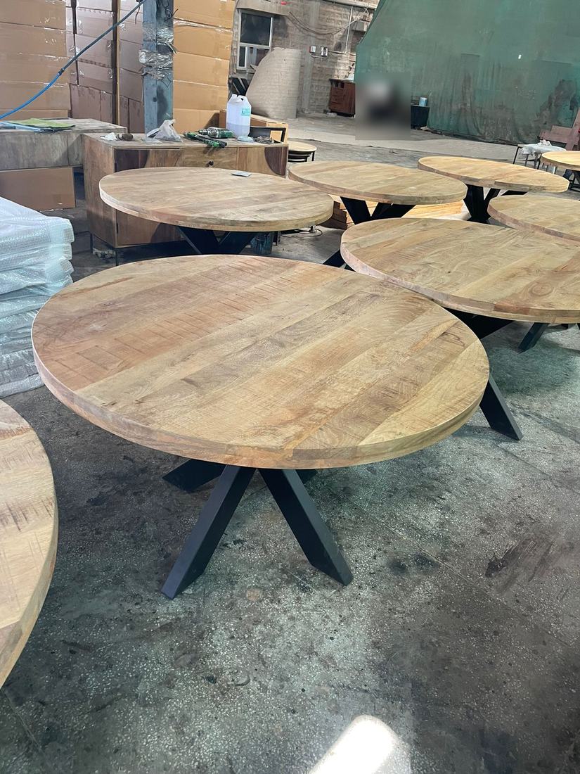 Round mango-wood dining tables on metal bases at inspection