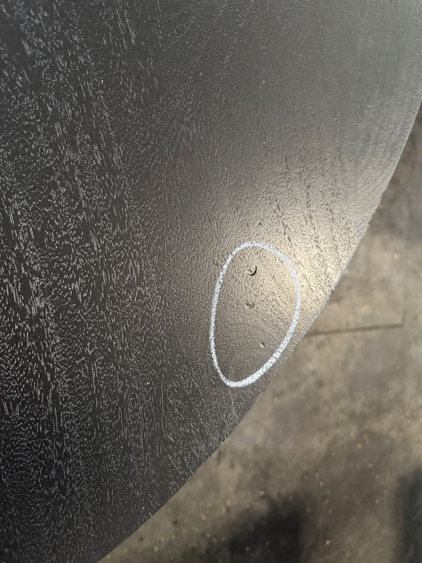 Small dents in a black finished round top, circled in chalk