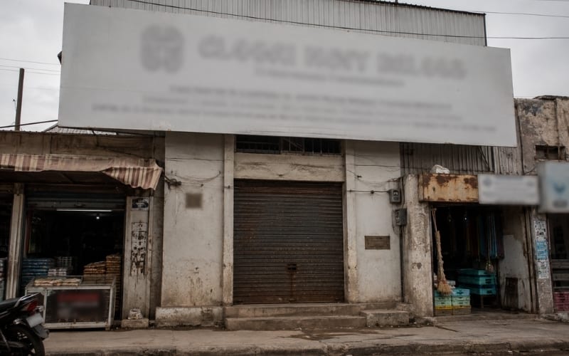 Locked shutter of a small trading office with a grand signboard — the "factory" that wasn't.