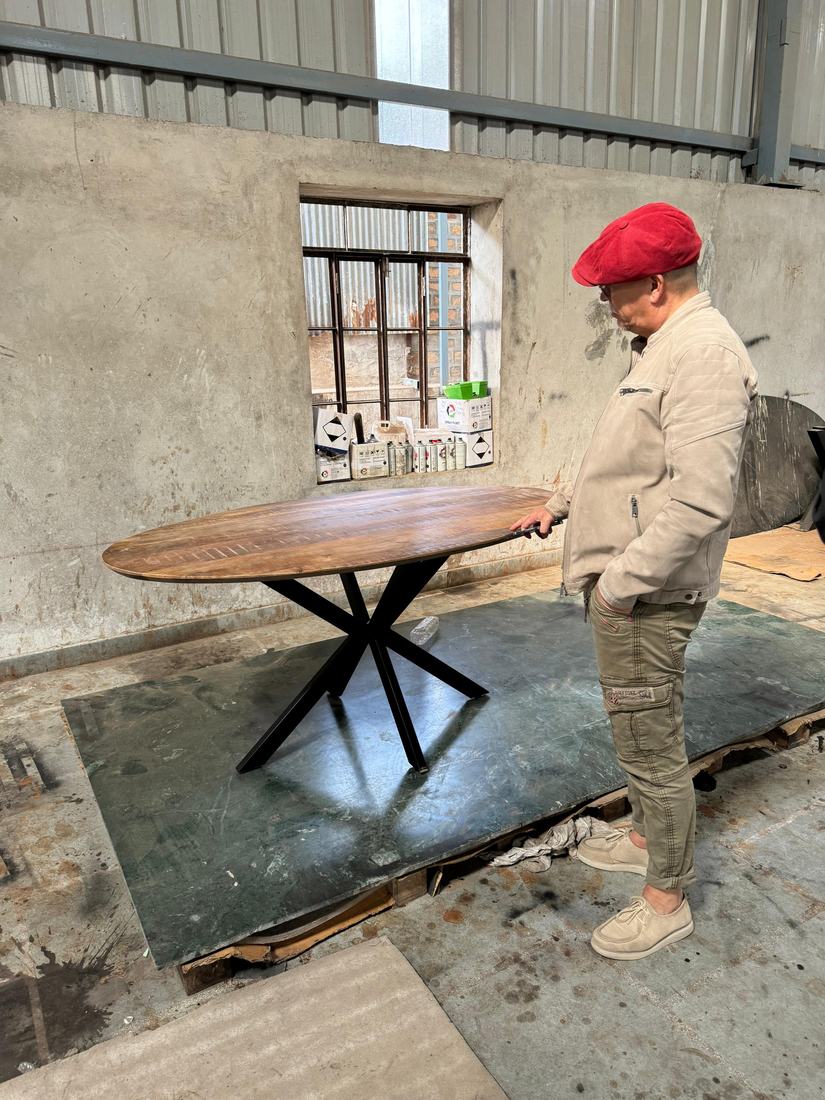 Checking the edge of an oval top on a metal base with the buyer
